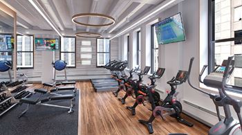 a gym with rows of exercise equipment and a tv